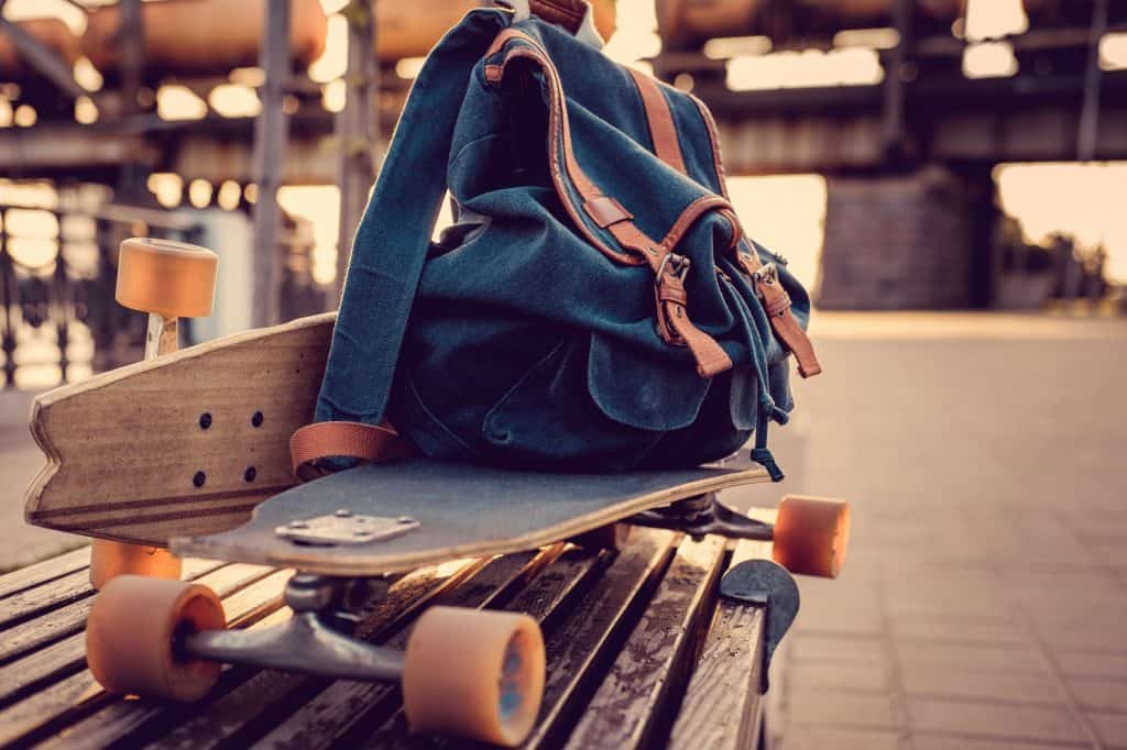 El significado de los sueños con mochilas y mochilas escolares. 6 Longboard y mochila en el banco.